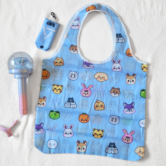 A blue tote bag with Seventeen's Miniteen characters on a white background. A 10th anniversary seventeen lightstick is on the left side. The tote storage clip-on bag is on the top-left of the image.