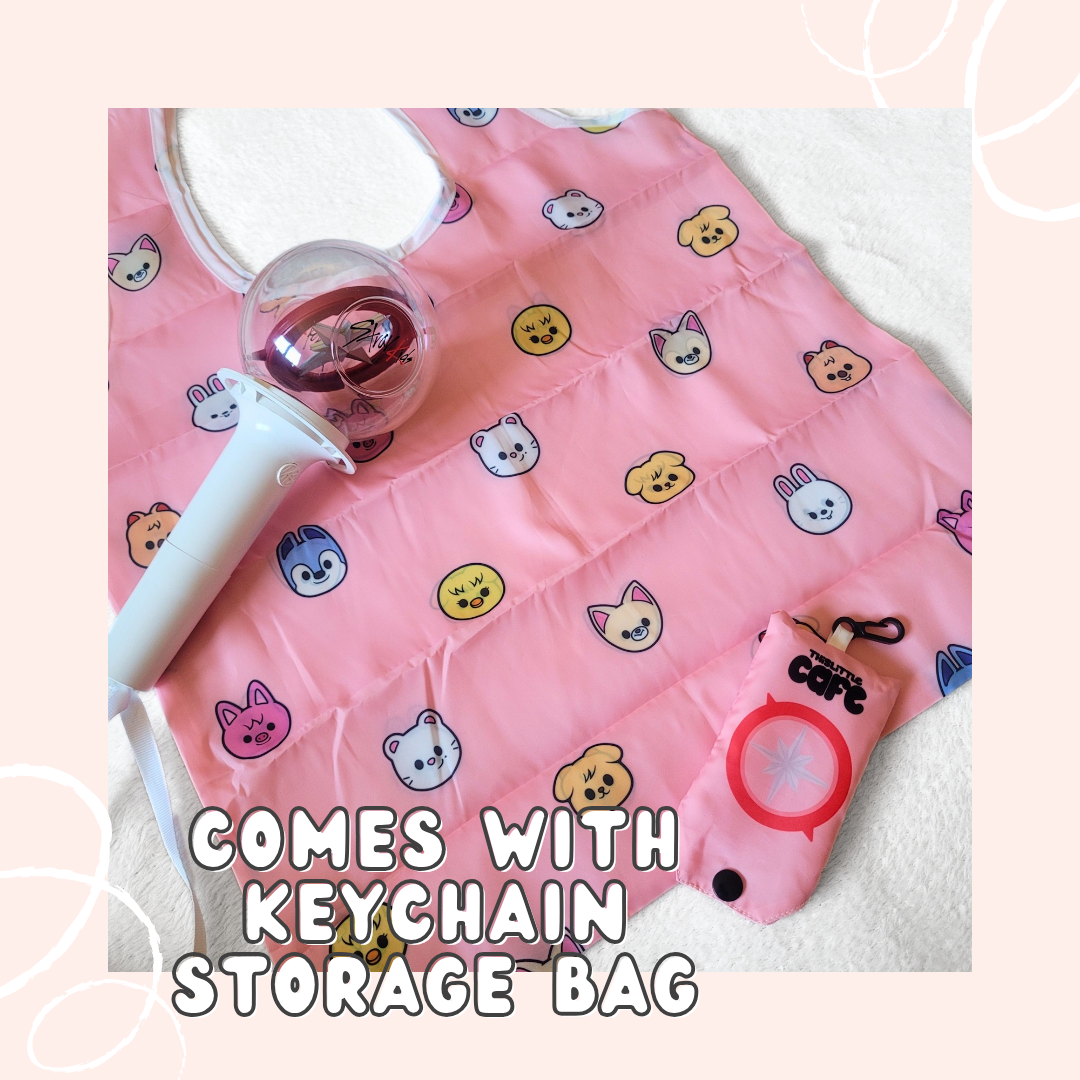 A pink tote bag with Stray Kid's Skzoo characters on a white background. A 1st generation stray kids lightstick is on the top-left side. The tote storage clip-on bag is on the bottom-right of the image. The words "COMES WITH KEYCHAIN STORAGE BAG" in white font are at the bottom with a light-pink background.